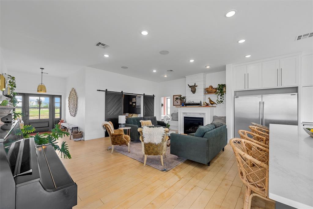 1197 Prairie Chapel Road Crawford, TX 76638 - Photo 9 of 40 Living area with a barn door, recessed lighting, light wood-style flooring, and a fireplace