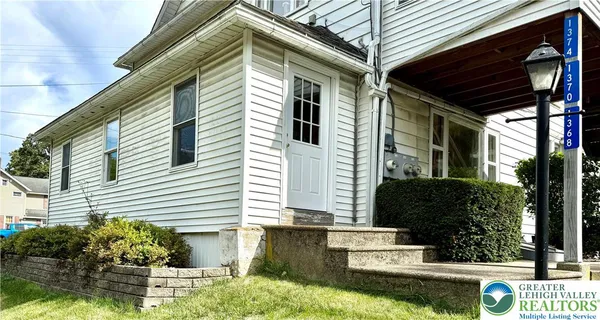 a view of a house with a yard and potted plants