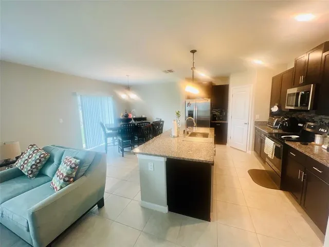 a kitchen with stainless steel appliances kitchen island granite countertop a refrigerator a stove and a sink with wooden floor