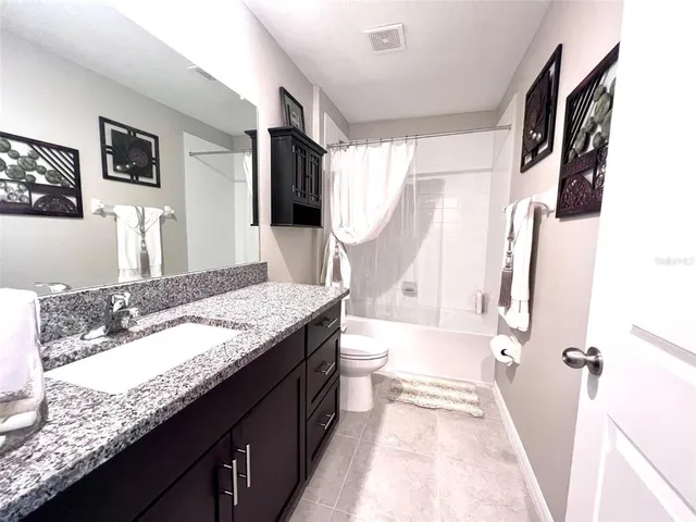 a bathroom with a granite countertop sink a mirror and shower