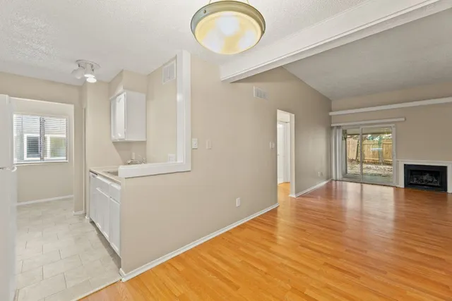 a view of an empty room with window and wooden floor