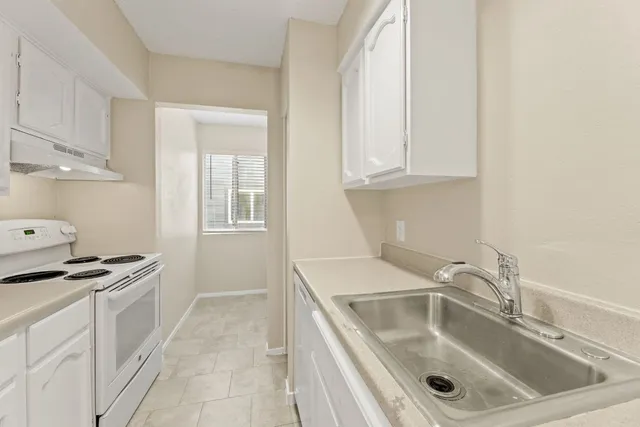 a kitchen with granite countertop a sink stove and cabinets