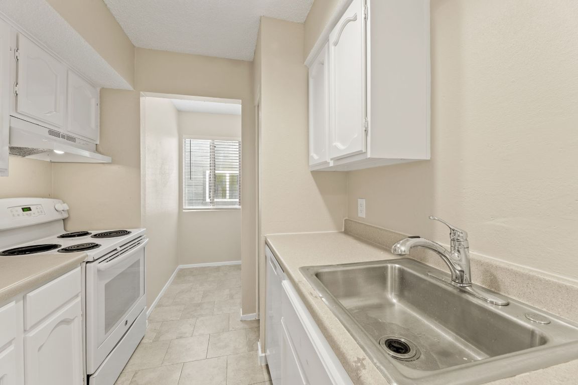 6901 Woodhue Drive, Unit A Austin, TX 78745 - Photo 18 of 34 a kitchen with granite countertop a sink stove and cabinets