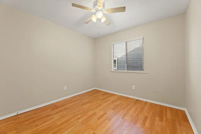 an empty room with a window and ceiling fan