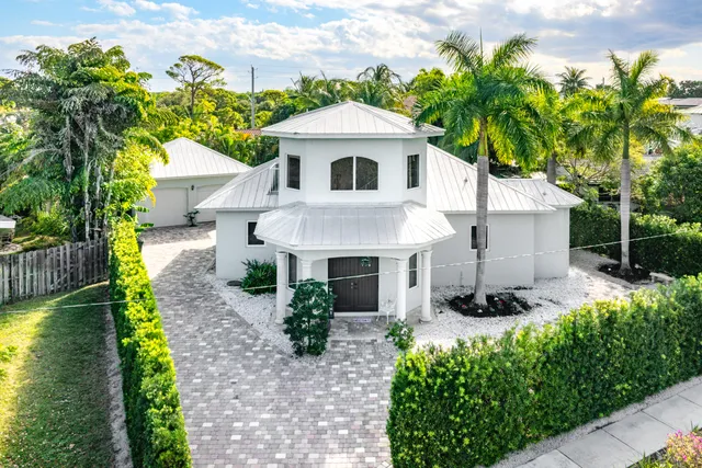 a front view of a house with a yard and potted plants