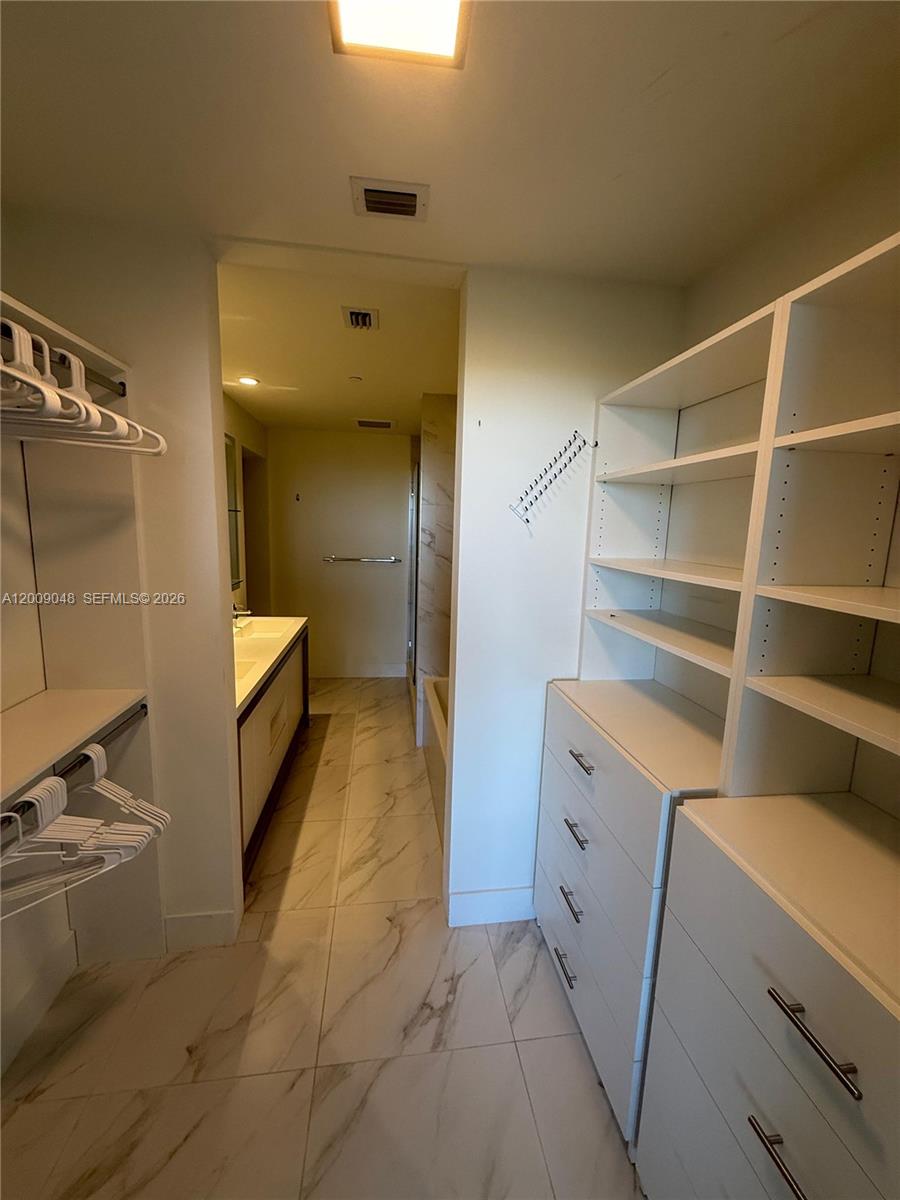 2000 Metropica Way, Unit 901 Sunrise, FL 33323 - Photo 7 of 25 a view of walk in closet with clothes and shoes