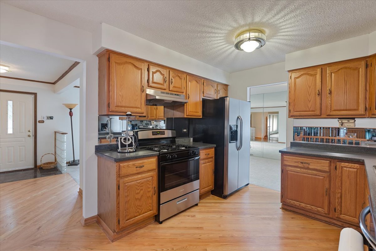 534 Quail Run Road Matteson, IL 60443 - Photo 11 of 31 a kitchen with stainless steel appliances granite countertop a stove top oven a refrigerator a sink a dining table and chairs with wooden floor