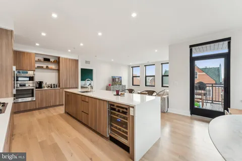 a large kitchen with a large counter top a sink a window and stainless steel appliances