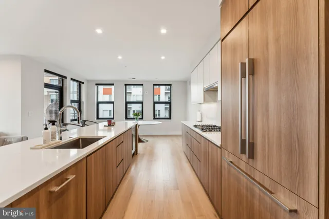 a large kitchen with stainless steel appliances a sink and cabinets