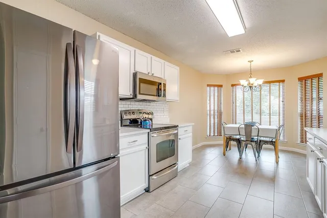 a kitchen with a refrigerator and table chairs