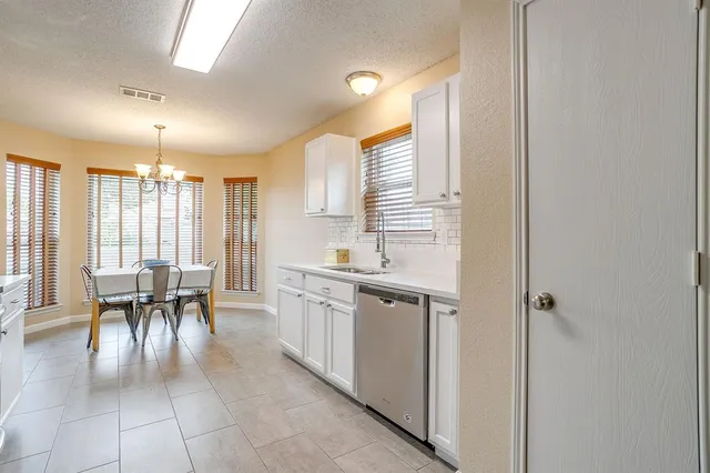 a dining hall with stainless steel appliances granite countertop a sink and cabinets