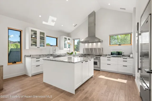 a kitchen with stainless steel appliances kitchen island granite countertop a stove a sink and a refrigerator