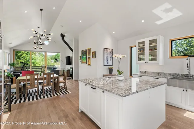 a kitchen with stainless steel appliances granite countertop sink stove and white cabinets with wooden floor