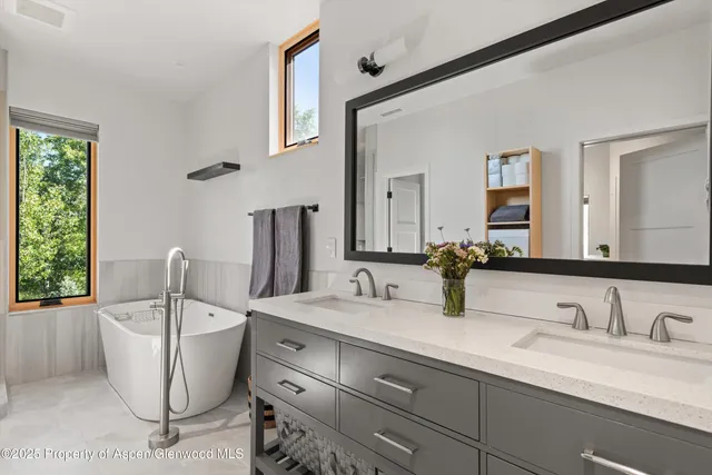 a bathroom with a double vanity sink a mirror and bathtub