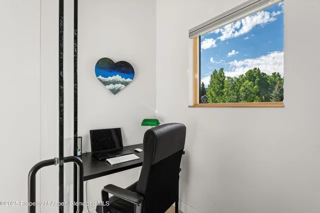 a view of a workspace with furniture and a window