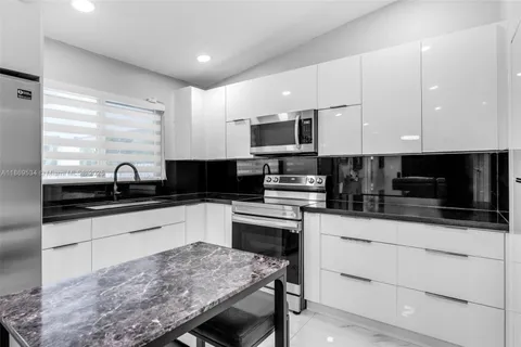 a kitchen with granite countertop white cabinets and black appliances