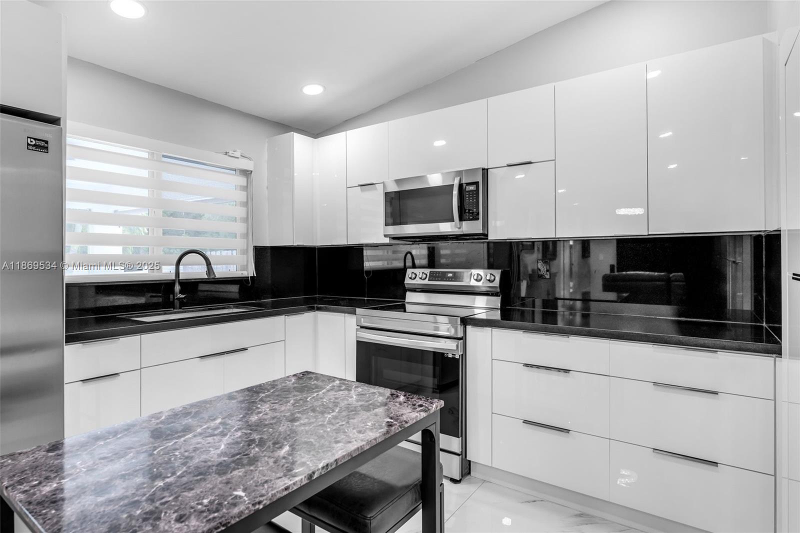 11186 Southwest 75th Terrace Miami, FL 33173 - Photo 3 of 26 a kitchen with granite countertop white cabinets and black appliances