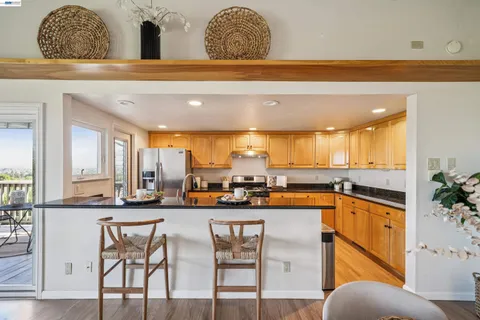 a dining hall with stainless steel appliances granite countertop a table and chairs