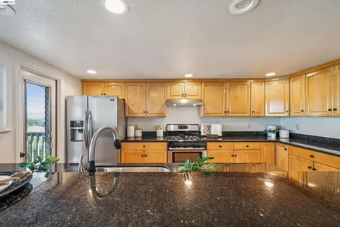 a kitchen with stainless steel appliances a refrigerator a sink a stove cabinets and a dining table