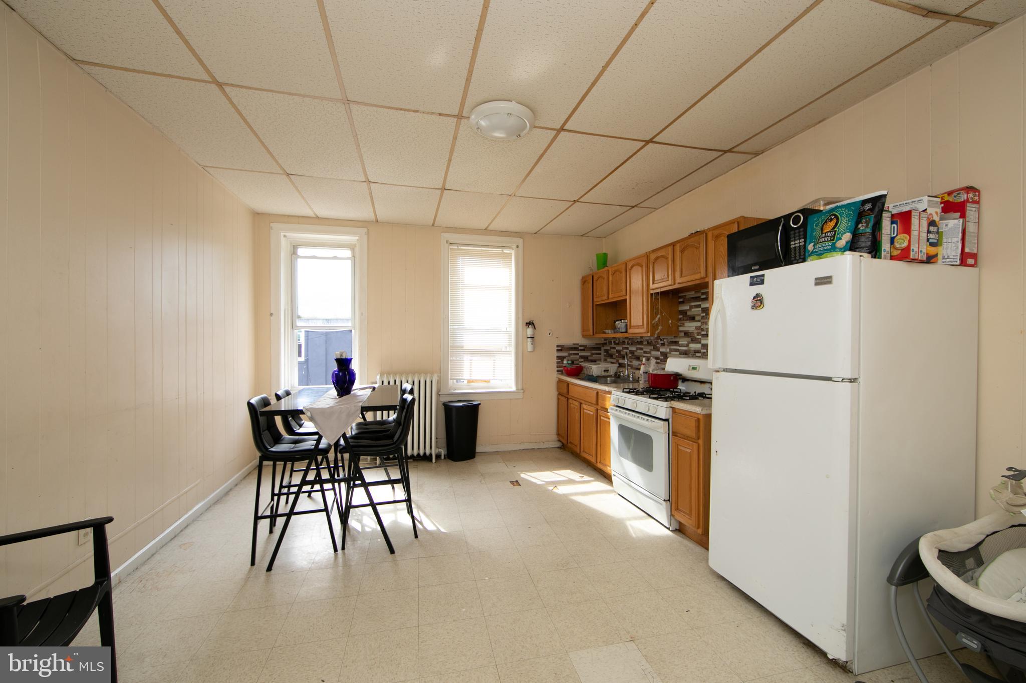 1574 Mt Ephraim Avenue Camden, NJ 08104 - Photo 37 of 54 a kitchen with a refrigerator a table and chairs