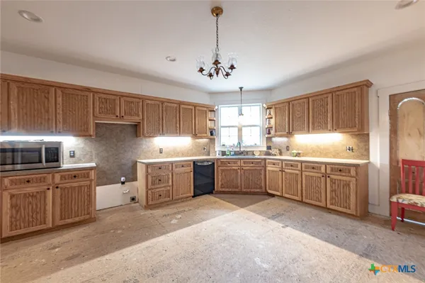 a kitchen with stainless steel appliances granite countertop a sink a stove a refrigerator cabinets and a window