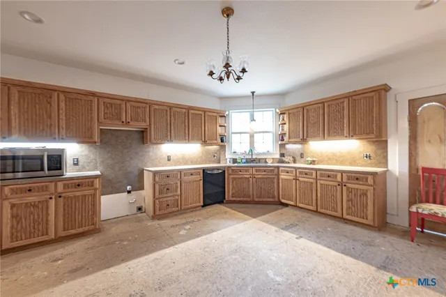 a kitchen with stainless steel appliances granite countertop a sink a stove a refrigerator cabinets and a window