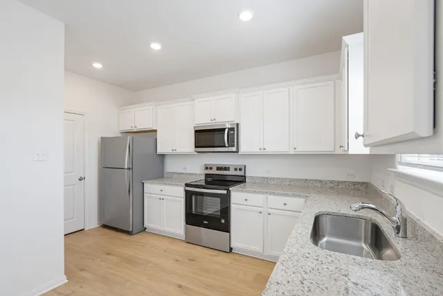 a kitchen with stainless steel appliances granite countertop a sink stove and refrigerator