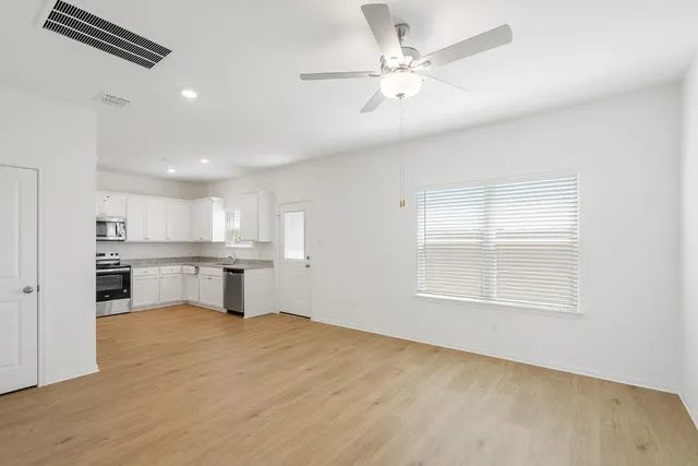 an empty room with windows and ceiling fan