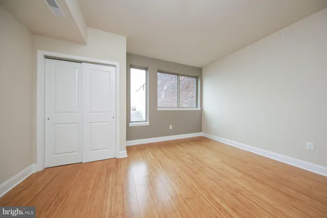 an empty room with wooden floor and windows