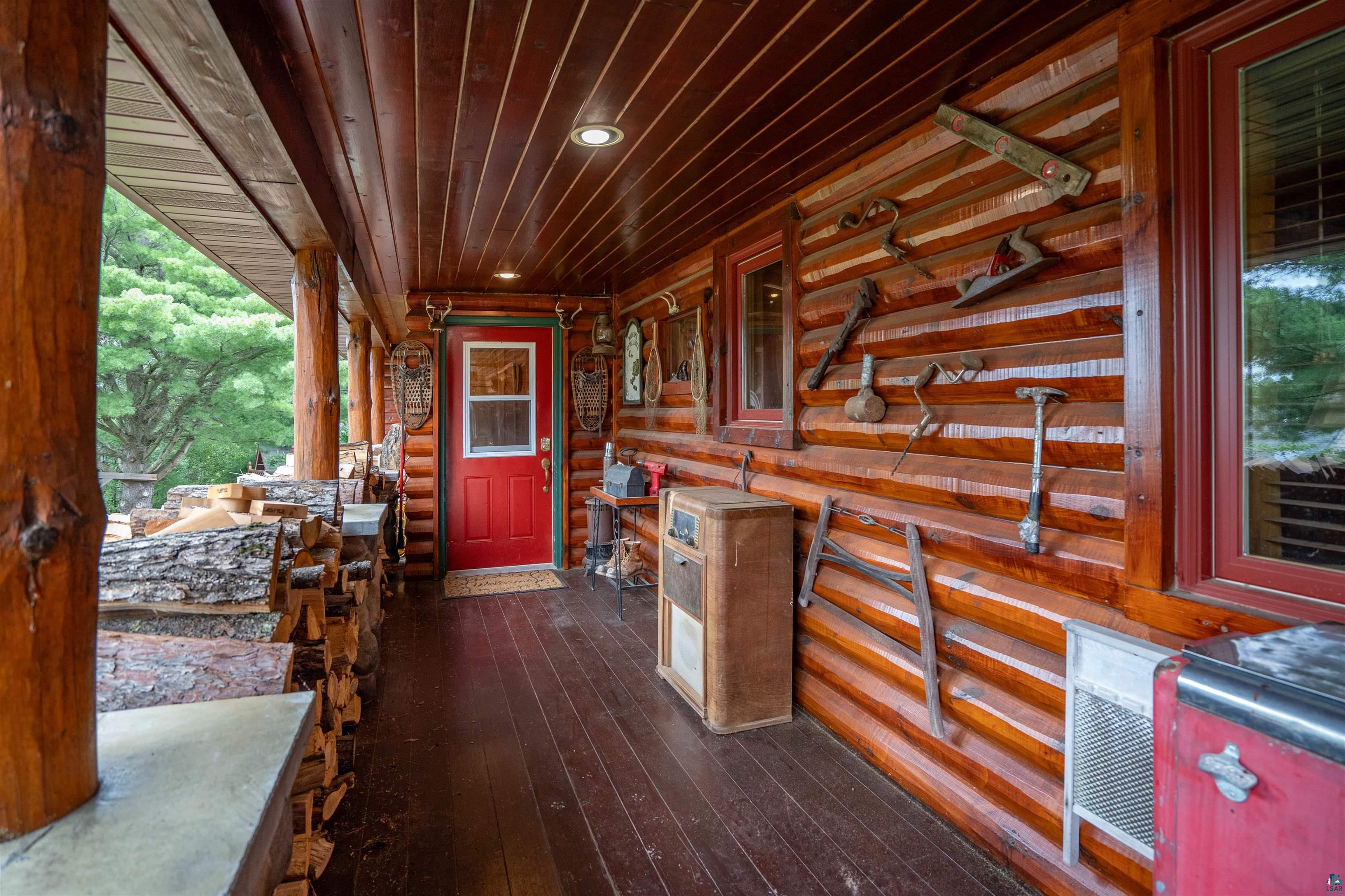 11911 East Rowe Road Lake Nebagamon, WI 54849 - Photo 27 of 61 Expansive covered porch featuring log construction, rich wood-finish flooring, a vibrant red entry door, and recessed lighting
