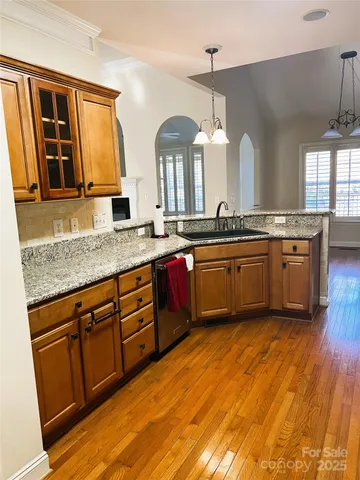 a large kitchen with stainless steel appliances granite countertop a sink dishwasher stove and wooden cabinets