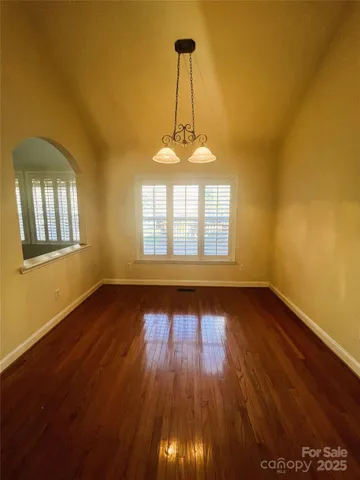 a view of a room with wooden floor a exposed radiator and a window