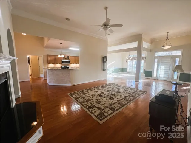a living room with stainless steel appliances furniture a rug and a view of kitchen