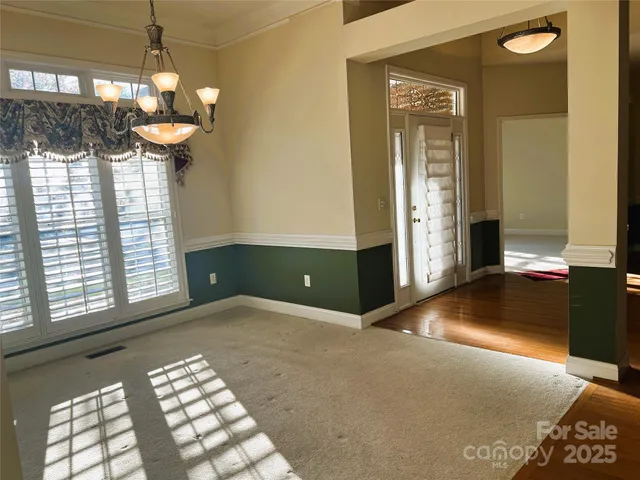 a view of an empty room with a fireplace and a chandelier