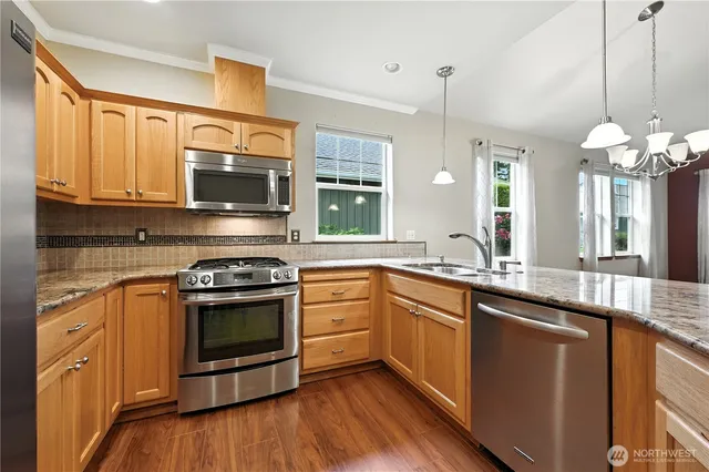 a kitchen with stainless steel appliances granite countertop a sink a stove a microwave and wooden floors