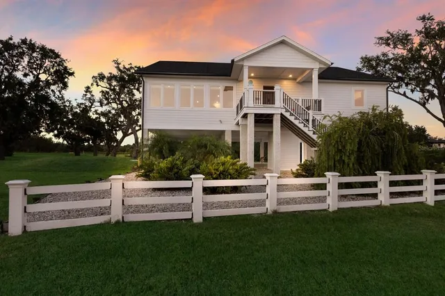 a view of a house with a yard and a large tree