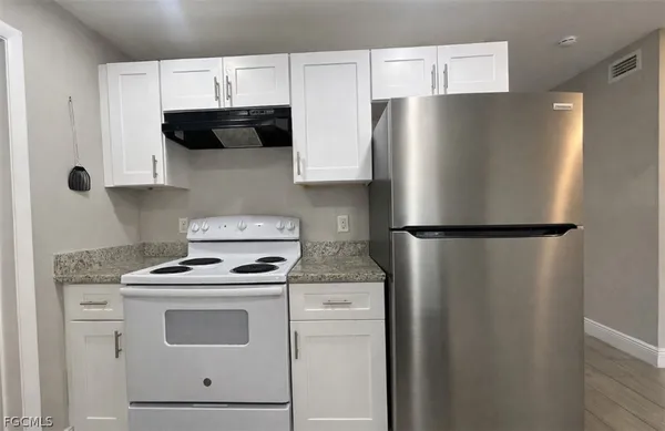 a kitchen with stainless steel appliances white cabinets and a refrigerator