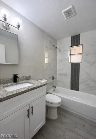 a bathroom with a granite countertop sink toilet and mirror