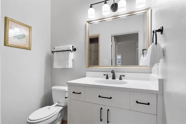 a bathroom with a sink vanity mirror and toilet