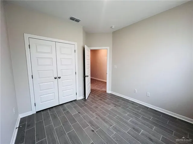 an empty room with wooden floor and closet area