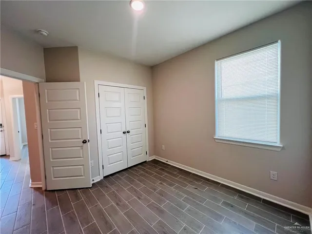 an empty room with wooden floor cabinet and windows