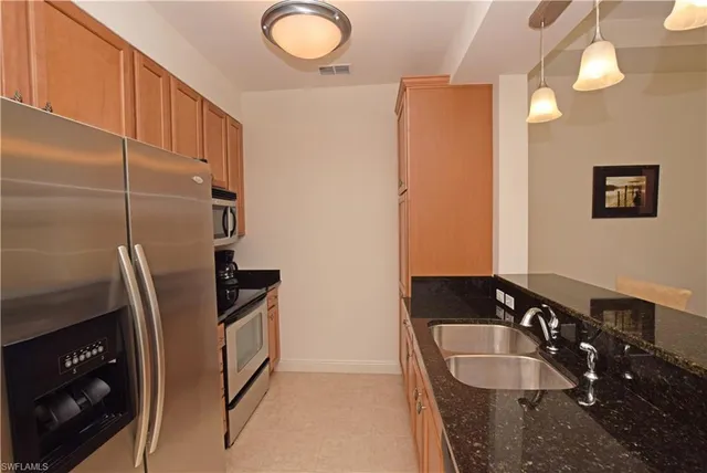 a kitchen with granite countertop a refrigerator a stove and a sink