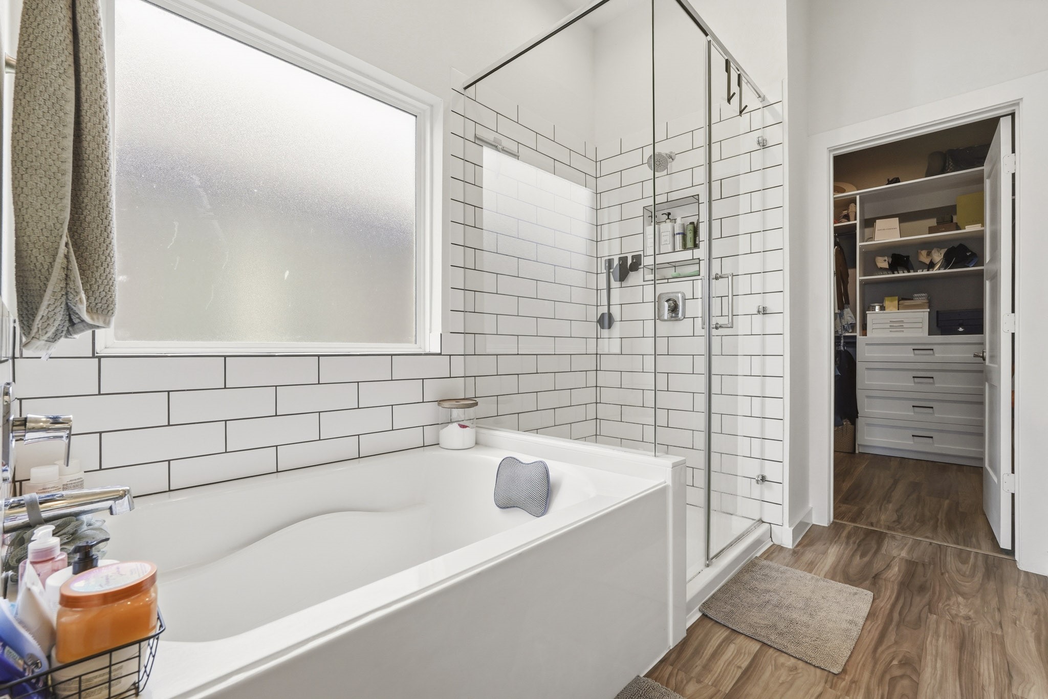 22522 Modica Rift Lane Katy, TX 77449 - Photo 23 of 38 Look at that tub. Nestled beside a frosted privacy window, the deep soaking tub is the kind of feature you don't know you need until you have it — and then you wonder how you ever lived without it. The adjoining frameless glass shower is fully tiled in classic white subway with bold dark grout, fitted with a rainfall-style showerhead and built-in niche. Together, they create a bathing experience that rivals any boutique hotel.