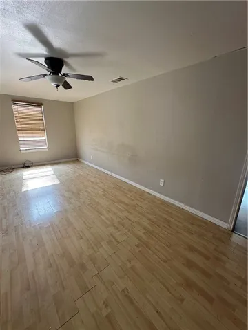 an empty room with wooden floor ceiling fan and windows
