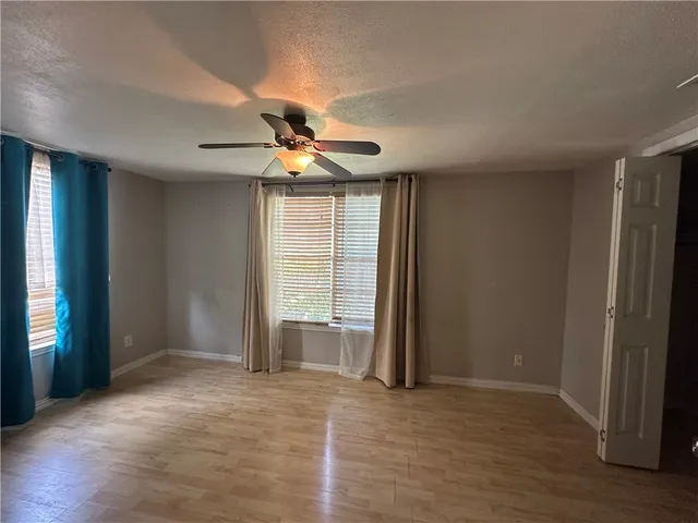 an empty room with wooden floor and windows