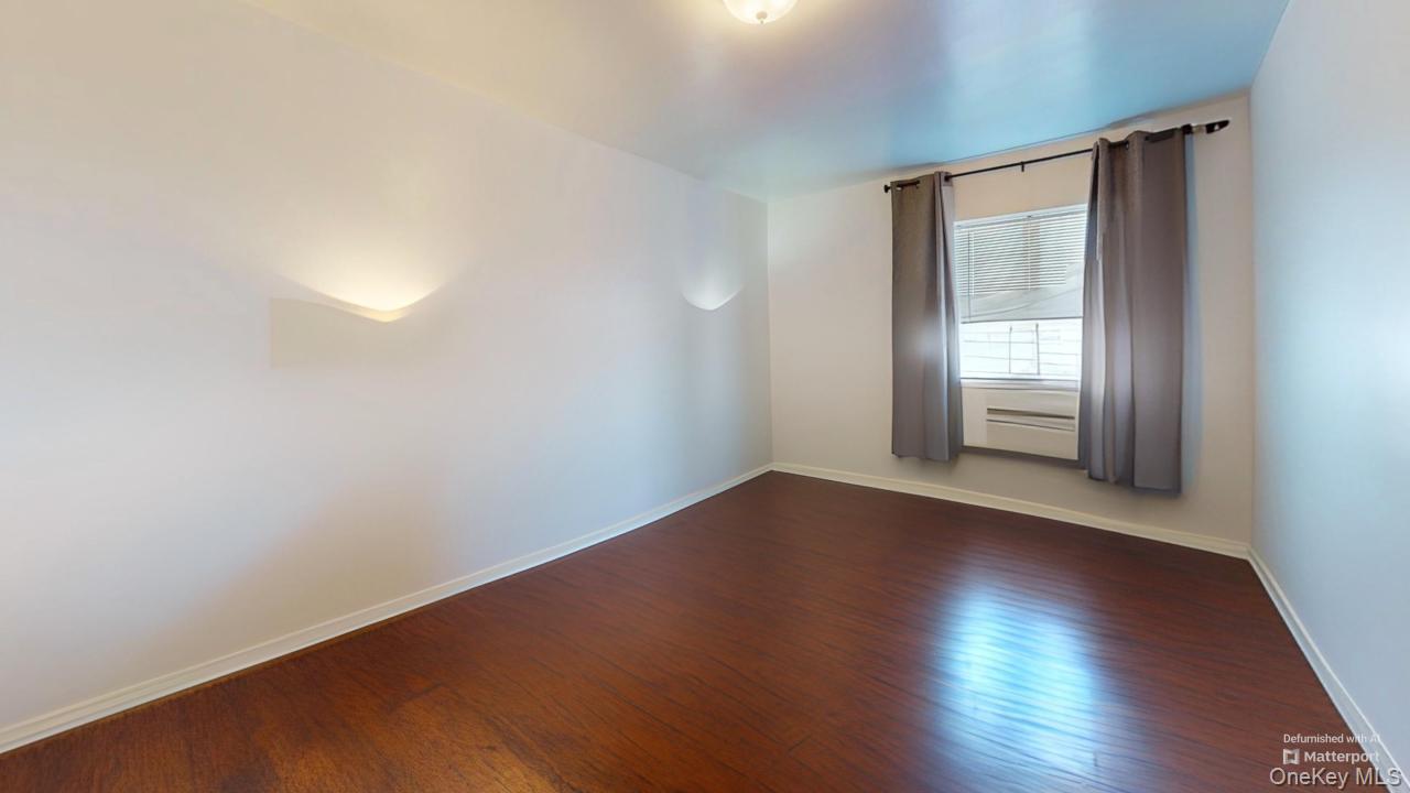 72-52 Metropolitan Avenue, Unit 3C Queens, NY 11379 - Photo 6 of 6 an empty room with wooden floor and windows