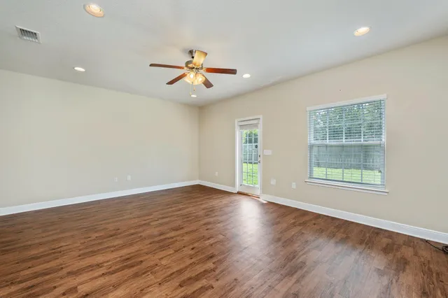 a view of an empty room with wooden floor and a window