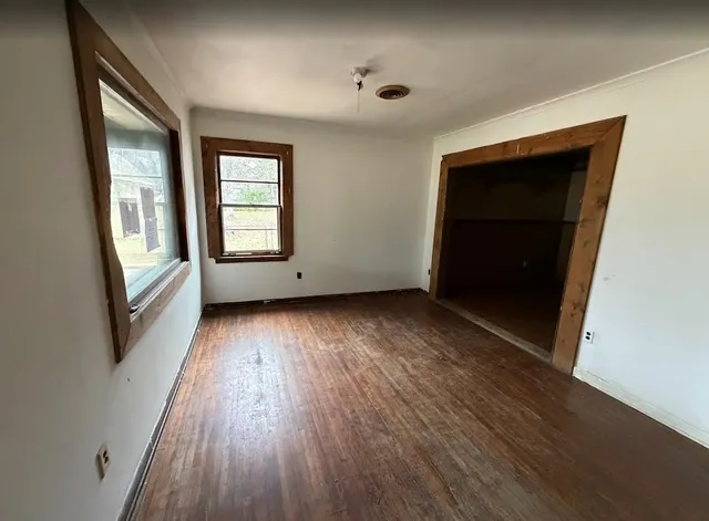 an empty room with wooden floor and windows