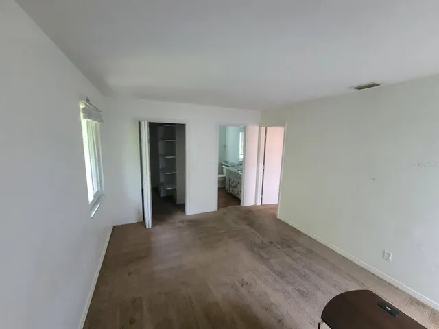 a view of an empty room with window and closet area