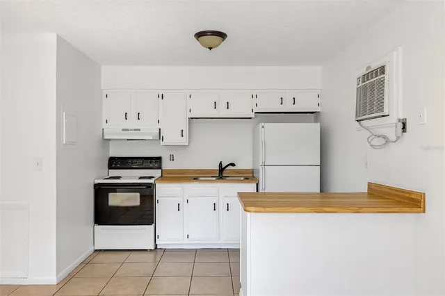a kitchen with granite countertop a sink a stove a refrigerator and white cabinets